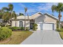 Tan one-story house with white garage door and palm trees at 750 Pond Lily Way, Venice, FL 34293