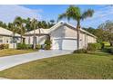 One-story home with a white garage door and lush landscaping at 750 Pond Lily Way, Venice, FL 34293