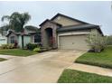 Tan house with stone accents, palm trees, and a two-car garage at 11854 Thicket Wood Dr, Riverview, FL 33579