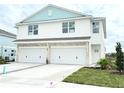 Two-story duplex with attached garages, light teal accents, and landscaping at 14016 Emerald Fields Dr, Hudson, FL 34667