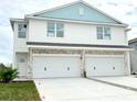 Two-story duplex with light blue accents, two-car garage, and driveway at 14024 Emerald Fields Dr, Hudson, FL 34667