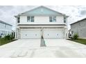 Two-story duplex with light blue accents, two-car garage, and driveway at 14024 Emerald Fields Dr, Hudson, FL 34667