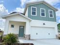 Two-story house with light teal and white siding, three-car garage, and landscaping at 7950 Chandler Lake Ct, Hudson, FL 34667