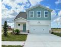 Two-story home with light teal and white siding, three-car garage, and landscaping at 7971 Chandler Lake Ct, Hudson, FL 34667