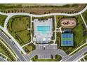Aerial view of community pool, tennis court, and playground amidst manicured landscaping at 7530 Backlight Ln, Sarasota, FL 34240