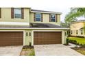 Two-car garage with brown doors and exterior lighting at 8609 Fiddleleaf Ct, Tampa, FL 33647