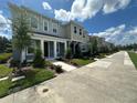 Row of townhouses with gray and beige siding, landscaping, and a walkway at 5046 Avalon Park Blvd, Wesley Chapel, FL 33545