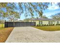Long driveway leading to a charming one-story home, offering ample parking and a stylish modern fence at 8600 W Knights Griffin Rd, Plant City, FL 33565