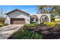 White stucco home with brown garage door and arched entryway at 4907 Parson Brown Ln, Palm Harbor, FL 34684