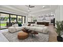 Bright open living room featuring a large sectional, modern finishes, and sliding glass doors to the backyard at 4327 Glendon Pl, Valrico, FL 33596