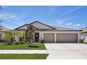 Single-story house featuring a three-car garage and well-manicured lawn at 288 Rain Berry Ave, Ruskin, FL 33570