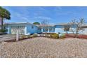 Light blue home exterior, landscaped yard, and pebble driveway at 909 Birdie Way, Apollo Beach, FL 33572