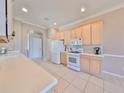 Bright kitchen features tile floors, modern appliances, light wood cabinets, and white countertops at 1007 Emerald Dunes Dr, Sun City Center, FL 33573