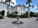 Cream-colored house with a circular driveway with fountain, lush greenery, and tall palm trees at 19451 Ganton Ave, Bradenton, FL 34202