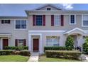 Two-story townhome featuring a red door and manicured lawn at 16410 Rollingbrook Dr, Odessa, FL 33556