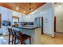 Modern white kitchen with island, stainless steel appliances, and wood ceiling at 17210 Orangewood Dr, Lutz, FL 33548