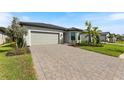 New construction home with gray siding, paver driveway and a two-car garage at 1877 Pepper Grass Dr, North Port, FL 34289