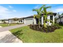 Modern home with gray siding, paver driveway, and a landscaped yard at 1877 Pepper Grass Dr, North Port, FL 34289