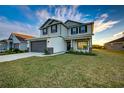 Two-story house with gray siding, dark garage door, and landscaped lawn at 16131 69Th Lane East, Parrish, FL 34219