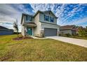 Two-story house with gray siding, teal accents, and a landscaped lawn at 16123 69Th E Ln, Parrish, FL 34219
