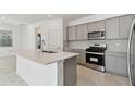 Modern kitchen with gray shaker cabinets, stainless steel appliances, and quartz countertops at 1279 Kazaz Ct, Zephyrhills, FL 33540