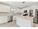 Modern kitchen with white cabinets, island, and stainless steel appliances at 1185 Kistna Dr, Zephyrhills, FL 33540