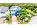 Two-story light blue house with paver driveway, landscaping, and a view of a nature preserve at 905 Seagrape Dr, Ruskin, FL 33570