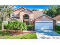 Two-story house with tan exterior, white garage door, and landscaped yard at 9083 Quail Creek Dr, Tampa, FL 33647