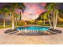 Luxury pool with fountains at sunset, surrounded by palm trees and landscape lighting at 10603 Low Oak Ter, Thonotosassa, FL 33592