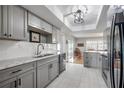 Modern kitchen with gray cabinets, marble countertops, and black appliances at 14542 Anchorage Cir, Seminole, FL 33776