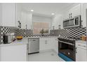 Modern kitchen with white cabinets, geometric backsplash, and stainless steel appliances at 2221 S Village Ave, Tampa, FL 33612