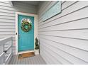 Teal front door with a wreath, welcome mat, and potted plants at 1118 2Nd S Ave, Tierra Verde, FL 33715