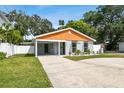 Modern house with gray and orange exterior, landscaped yard, and driveway at 4607 W San Jose St, Tampa, FL 33629