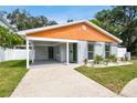 Modern house with gray and orange exterior, landscaped yard, and driveway at 4607 W San Jose St, Tampa, FL 33629