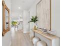 Bright and airy entryway with light hardwood floors, console table, and large artwork at 6258 Broad Field Ave, Apollo Beach, FL 33572