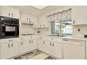 Traditional kitchen with white cabinets, neutral countertops, and modern appliances at 13084 Drysdale St, Spring Hill, FL 34609