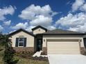 Inviting single-story home featuring stone accents, a manicured lawn, and a two-car garage at 8135 Tea Olive Ter, Palmetto, FL 34221