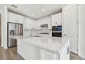 Modern kitchen featuring white cabinets, stainless steel appliances, and a large island at 13728 Sunlight Meadow Dr, Riverview, FL 33578