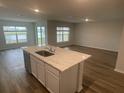 Open concept kitchen with island, white cabinets, and view into living area at 6223 Distant Haze Pl, Palmetto, FL 34221