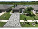 House with a paver driveway, landscaping, and a view of a lake at 5429 Rainwood Meadows Dr, Apollo Beach, FL 33572