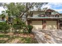 Two-story townhome with two-car garage, lush landscaping, and a brick facade at 1500 Mahogany Ln # 605, Palm Harbor, FL 34683