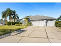 Three-car garage and driveway with palm trees and landscaping at 8929 Cashella Ct, Trinity, FL 34655