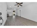 Bright living room featuring modern gray flooring, a ceiling fan, and white walls at 541 E Lime St, Tarpon Springs, FL 34689