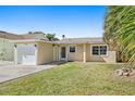 Cute bungalow features a one car garage and a well manicured lawn at 17710 Long Point Dr, Redington Shores, FL 33708