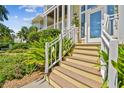 Charming home entrance with wood stairs, white railings, and vibrant, colorful landscaping at 6231 Bayshore Blvd, Tampa, FL 33611