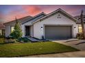 Inviting home with a well-maintained lawn, neutral exterior, and a two-car garage under a colorful sky at 4658 Freccia Loop, Wesley Chapel, FL 33543