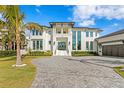 Gorgeous home featuring a pristine white facade, a three-car garage, tropical landscaping, and a paver driveway at 105 Cordova Ne Blvd, St Petersburg, FL 33704