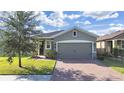 Gray one-story house with a two-car garage and landscaped front yard at 11633 Mandevilla View Way, Riverview, FL 33579