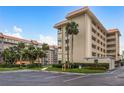 Tan multi-story building with palm trees and parking lot at 620 Edgewater Dr # 304, Dunedin, FL 34698