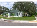 Corner view of a quaint light-green home with lush landscaping, green shutters and a sidewalk at 701 38Th N Ave, St Petersburg, FL 33704